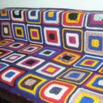 Couverture à carreaux sur le canapé à partir de motifs carrés tricotés