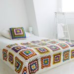 Grand plaid sur un lit avec des motifs de fleurs au crochet