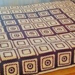 Belle couverture sur un grand lit d'éléments tricotés bicolores
