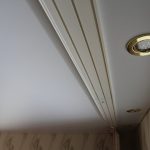 Corniche de plafond avec fixation sur une poutre en bois et éclairage au plafond