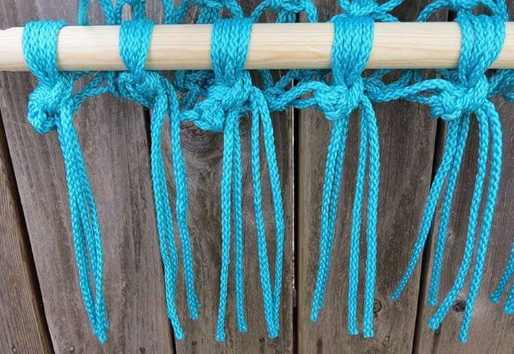 Tissage de noeuds de corde turquoise sur un bâton en bois